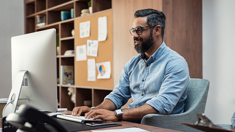 business man smiling and using desktop computer in office